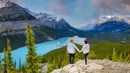 Téléchargez les photos : Lac Peyto Parc national Banff Canada. Mountain Lake comme Fox Head est populaire parmi les touristes au Canada conduisant la promenade des Glaciers. un couple d'hommes et de femmes regardant au-dessus du lac de couleur turqouse - en image libre de droit
