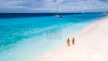Téléchargez les photos : Klein Curaçao île avec plage de sable blanc tropical à l'île caribéenne de Curaçao Caraïbes, un couple d'hommes et de femmes marchant sur la plage de la petite île de Curaçao à la turqouse couleur océan - en image libre de droit