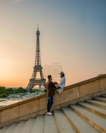 Téléchargez les photos : Jeune couple par Tour Eiffel à Sunrise Paris Eifel Towe, homme femme amoureuse concept valentin à Paris la ville de l'amour. Hommes et femmes visitant la Tour Eiffel voyage de noces - en image libre de droit
