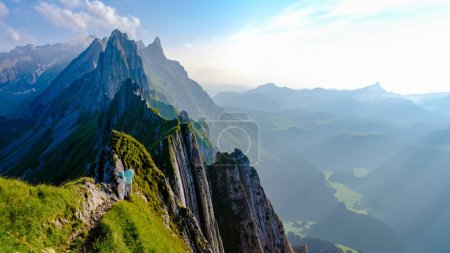 Foto de Schaeffler Mountain Ridge Swiss Alpstein Appenzell Switzerland, una cresta del majestuoso pico Schaeffler de Berggasthaus Schafler Switzerland. una pareja de hombres y mujeres en las montañas durante la puesta del sol - Imagen libre de derechos