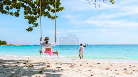 Foto de Un par de hombres y mujeres en un columpio en la playa de Koh Samet Island Rayong Tailandia, la playa tropical blanca de Samed Island con un océano de color turquesa. Mujer asiática y hombres europeos de vacaciones - Imagen libre de derechos