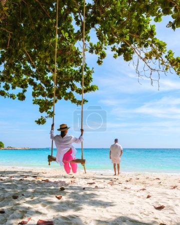 Téléchargez les photos : Un couple d'hommes et de femmes à une balançoire sur la plage de Koh Samet Island Rayong Thaïlande, la plage tropicale blanche de Samed Island avec un océan de couleur turque. Femme asiatique et les hommes européens en vacances - en image libre de droit
