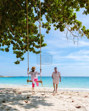 Photo for A couple of men and women at a swing on the beach of Koh Samet Island Rayong Thailand, the white tropical beach of Samed Island with a turqouse colored ocean. - Royalty Free Image