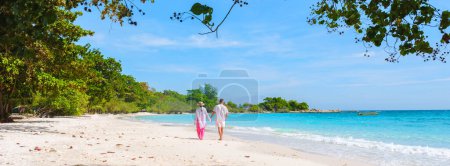 Téléchargez les photos : Un couple d'hommes et de femmes marchant sur la plage de l'île de Koh Samet en Thaïlande, la plage tropicale blanche de l'île de Samed avec un océan de couleur turque, femme thaïlandaise asiatique et hommes européens sur la plage - en image libre de droit