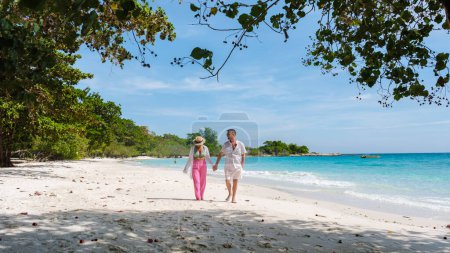 Photo for A couple of men and woman walking on the beach of Koh Samet Island Thailand, the white tropical beach of Samed Island with a turqouse colored ocean, Asian Thai woman and European men on the beach - Royalty Free Image