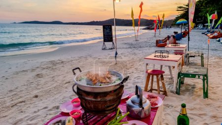 Téléchargez les photos : Koh Samet Island Rayong Thaïlande 10 décembre 2023, une plage tropicale avec une turque couleur océan à Samed Island au coucher du soleil avec chaises longues dans un restaurant sur la plage - en image libre de droit