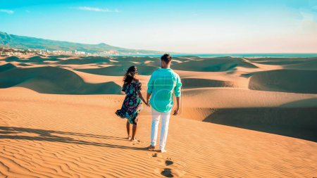Photo for Couple walking at the beach of Maspalomas Gran Canaria Spain, men and woman at the sand dunes desert of Maspalomas Spain Europe in the morning sun during sunrise - Royalty Free Image