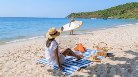 Téléchargez les photos : Koh Larn Island près de Pattaya Thaïlande, la plage tropicale de Koh Larn Thaïlande, une plage de sable blanc avec un océan d'eau claire. Tropical Island. un couple d'hommes se relaxant sur la plage avec un sup board - en image libre de droit