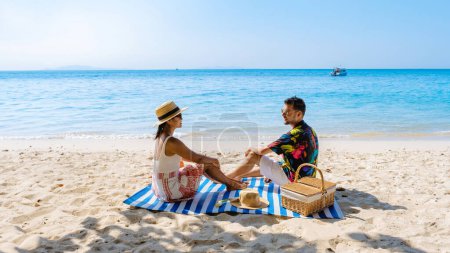 Foto de Isla Koh Larn cerca de Pattaya Tailandia, la playa tropical de Koh Larn Tailandia, una playa blanca con océano de agua clara. Isla Tropical. un par de hombres relajándose en la playa con un picnic - Imagen libre de derechos