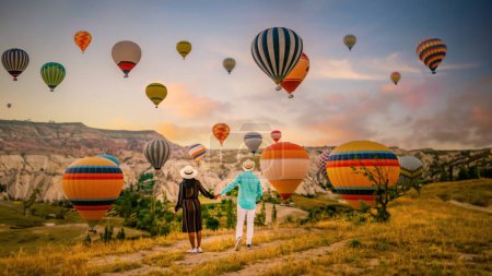 Téléchargez les photos : Cappadoce Turquie au lever du soleil, un couple d'hommes et de femmes d'âge moyen en vacances dans les collines de Goreme Cappadoce Turquie, hommes et femmes à la recherche lever du soleil avec des montgolfières en Cappadoce Turquie - en image libre de droit