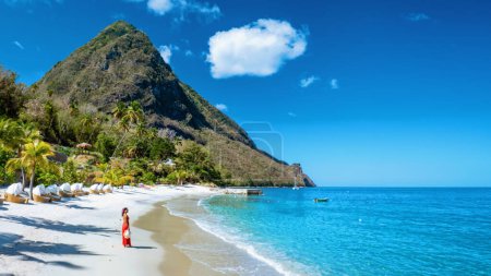 Téléchargez les photos : Sainte-Lucie Caraïbes, femme en vacances à l'île tropicale de Sainte-Lucie océan des Caraïbes, une femme asiatique en robe rouge marchant sur la plage - en image libre de droit