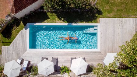Téléchargez les photos : Deux personnes nagent dans la piscine de l'hôtel. Vue d'en haut d'un couple d'hommes et de femmes dans une piscine d'une maison de vacances de luxe en France Europe - en image libre de droit