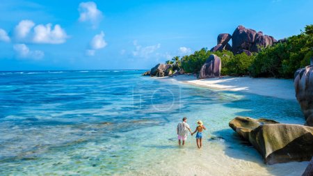 Téléchargez les photos : Anse Source d'Argent plage La Digue Island Seychelles, un couple d'hommes et de femmes marchant sur la plage lors de vacances de luxe. un couple nageant dans la turquouse colorée de l'océan de La Digue Seychelles - en image libre de droit