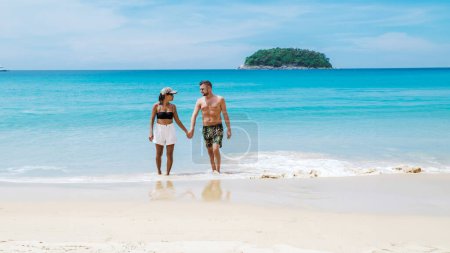 Téléchargez les photos : Couple diversifié marchant sur la plage de Kata Phuket Thaïlande pendant les vacances, hommes et femmes heureux en vacances en Thaïlande marchant sur l'océan de Kata Beach Phuket - en image libre de droit