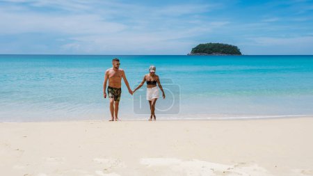 Foto de Pareja madura caminando en la playa de Kata Phuket Tailandia durante las vacaciones, hombres y mujeres felices de vacaciones en Tailandia caminando por el océano de Kata Beach Phuket - Imagen libre de derechos