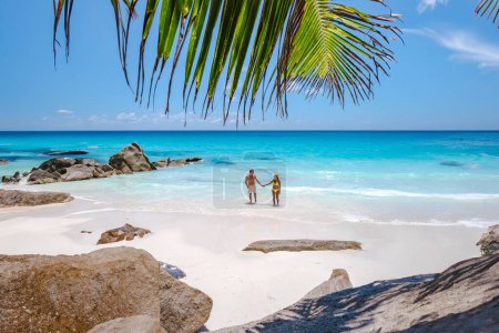 Foto de Anse Source d 'Argent beach La Digue Island Seychelles, un par de hombres y mujeres caminando por la playa en unas vacaciones de lujo. una pareja nadando en el turqouse océano de color - Imagen libre de derechos