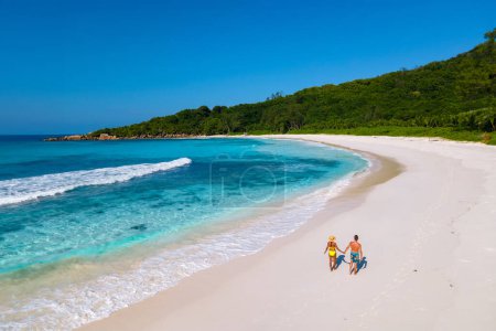 Téléchargez les photos : Anse Cocos plage La Digue Island Seychelles, Drone vue aérienne de La Digue Seychelles vue aérienne d'une île tropicale, un couple d'hommes et de femmes marchant sur la plage pendant le coucher du soleil lors de vacances de luxe - en image libre de droit