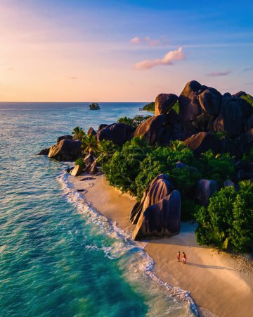 Téléchargez les photos : Anse Source d'Argent plage La Digue Island Seychelles, Drone vue aérienne de La Digue Seychelles vue aérienne de l'île tropicale, couple hommes et femmes marchant sur la plage au coucher du soleil - en image libre de droit