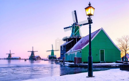 village de moulins à vent couvert de neige dans le Zaanse Schans Pays-Bas, moulins à vent historiques en bois en hiver Zaanse Schans Hollande pendant l'hiver temps au lever du soleil avec de la neige