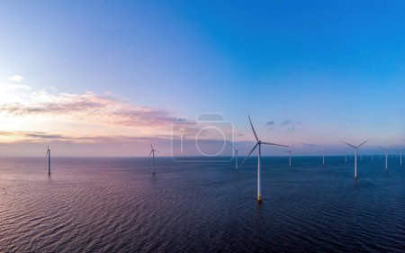 Photo for Windmill turbines generating electric green energy with a blue sky green energy concept in the Netherlands at sunset - Royalty Free Image