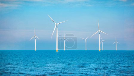Photo for Windmill turbines generating electric green energy with a blue sky green energy concept in the Netherlands, windmill turbines at sea - Royalty Free Image
