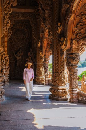 Téléchargez les photos : Les femmes asiatiques visitent le temple en bois du Sanctuaire de la Vérité à Pattaya Thaïlande, sculpture du temple du Sanctuaire de la Vérité. - en image libre de droit