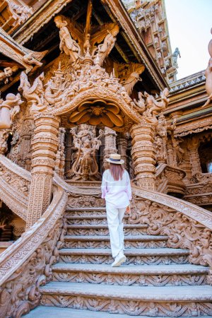 Photo for Asian women with hat visit The Sanctuary of Truth wooden temple in Pattaya Thailand, sculpture of Sanctuary of Truth temple. - Royalty Free Image