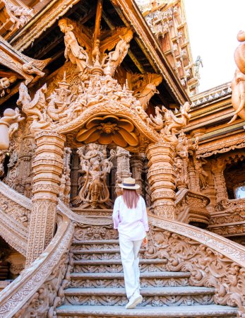 Téléchargez les photos : Les femmes asiatiques visitent le temple en bois du Sanctuaire de la Vérité à Pattaya Thaïlande, une sculpture en bois du temple du Sanctuaire de la Vérité. - en image libre de droit