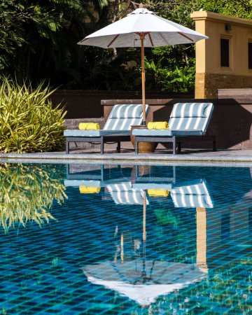 Téléchargez les photos : Parasol et chaises longues de luxe au bord de la piscine d'un hôtel de luxe - en image libre de droit
