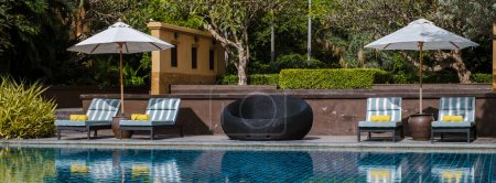 Téléchargez les photos : Parasol et chaises longues de luxe au bord de la piscine d'un hôtel de luxe - en image libre de droit