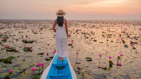 Téléchargez les photos : La mer de lotus rouge, Lac Nong Harn, Udon Thani, Thaïlande. Femme asiatique avec chapeau et robe sur un bateau au lac de lotus rouge dans l'Isaan - en image libre de droit