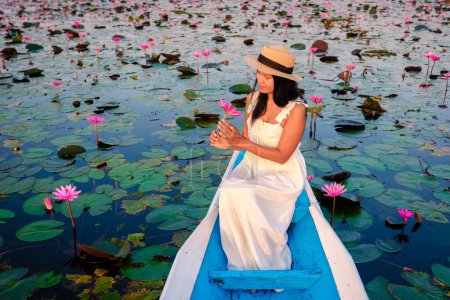 Photo for The sea of red lotus, Lake Nong Harn, Udon Thani, Thailand. Asian woman with hat and dress on a boat at the red lotus lake in the Isaan - Royalty Free Image