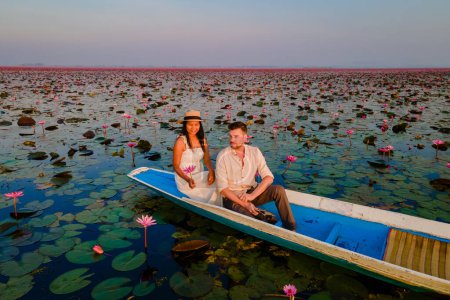 Photo for The sea of red lotus, Lake Nong Harn, Udon Thani, Thailand, a couple of men and woman in a boat at sunrise at the Red Lotus Lake in the Isaan - Royalty Free Image