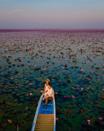 Foto de Salida del sol en el mar de loto rojo, Lago Nong Harn, Udon Thani, Tailandia, un par de hombres y mujeres en un barco al amanecer en el Lago de Loto Rojo en el Isaan - Imagen libre de derechos