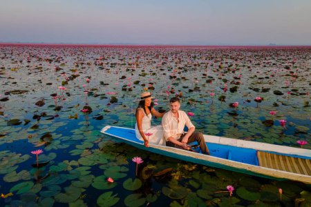 Téléchargez les photos : La mer de lotus rouge, lac Nong Harn, Udon Thani, Thaïlande, un couple d'hommes et de femmes dans un bateau au lever du soleil au lac Lotus rouge dans l'Isaan au lever du soleil - en image libre de droit