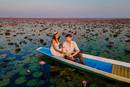 Téléchargez les photos : Lever du soleil à la mer de lotus rouge, lac Nong Harn, Udon Thani, Thaïlande, un couple d'hommes et de femmes dans un bateau au lever du soleil au lac Lotus rouge dans l'Isaan - en image libre de droit