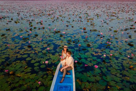 Téléchargez les photos : Drone vue aérienne à la mer du lotus rouge, lac Nong Harn, Udon Thani, Thaïlande, un couple d'hommes et de femmes dans un bateau au lever du soleil au lac Lotus rouge dans l'Isaan - en image libre de droit