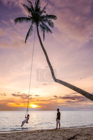 Téléchargez les photos : Tropical Island Koh Kood ou Koh Kut Thaïlande. Couple hommes et femmes en vacances en Thaïlande marchant sur la plage, concept de vacances Island hopping en Thaïlande orientale Trang, couple avec une balançoire à corde - en image libre de droit