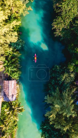 Téléchargez les photos : Couple hommes et femmes colportant en kayak pendant l'après-midi au coucher du soleil, Les gens dans un kayak à une rivière klong d'une île tropicale Koh Chang Thaïlande pendant le coucher du soleil dans la jungle de la forêt tropicale - en image libre de droit