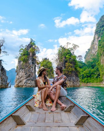 Téléchargez les photos : Un couple d'hommes et de femmes devant un bateau à queue longue à Khao Sok Thaïlande, montagnes panoramiques sur le lac dans le parc national de Khao Sok Asie du Sud-Est, hommes et femmes en excursion en bateau - en image libre de droit