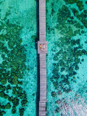 Foto de Pareja en un muelle de madera en el océano de Koh Kham Trat Tailandia, vista aérea de la isla tropical cerca de Koh Mak Tailandia. vista superior a un hombre y una mujer acostados en un embarcadero de madera, vista de pájaro - Imagen libre de derechos
