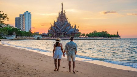 Téléchargez les photos : Un couple multiethnique diversifié d'hommes et de femmes visitent le temple en bois du Sanctuaire de la Vérité à Pattaya Thaïlande - en image libre de droit