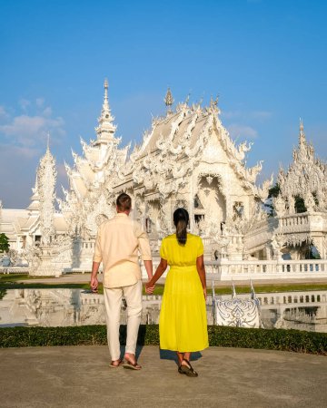 Téléchargez les photos : White Temple Chiang Rai Thaïlande, un couple diversifié d'hommes et de femmes visitent le temple Wat Rong Khun, Nord de la Thaïlande. - en image libre de droit