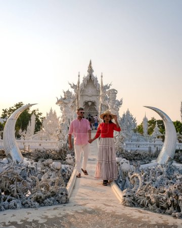 Téléchargez les photos : White Temple Chiang Rai Thaïlande, un couple diversifié d'hommes et de femmes visitent le temple Wat Rong Khun dans le nord de la Thaïlande. - en image libre de droit
