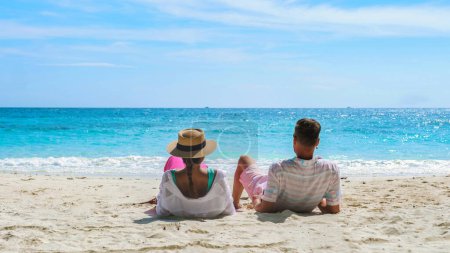 Foto de Un par de hombres y mujeres sentados en la playa mirando hacia el océano de Koh Samet Island Rayong Tailandia, la playa tropical blanca de Samed Island con un océano de color turquesa en un día soleado - Imagen libre de derechos