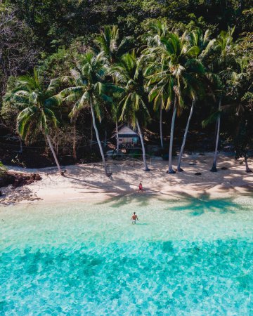 Téléchargez les photos : Koh Wai Island Trat Thaïlande une île tropicale près de Koh Chang. bungalow en bois de cabane de bambou sur la plage avec des palmiers. un jeune couple d'hommes et de femmes sur une île tropicale en Thaïlande - en image libre de droit