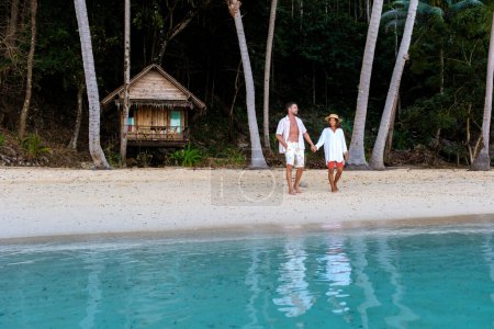 Téléchargez les photos : Koh Wai Island Trat Thaïlande près de Koh Chang. couple marchant devant un bungalow en bois de cabane de bambou sur la plage. un jeune couple d'hommes et de femmes sur une île tropicale en Thaïlande - en image libre de droit