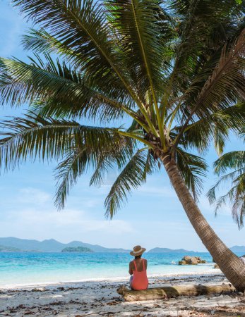 Téléchargez les photos : Koh Wai Island Trat Thaïlande est une île tropicale minuscule près de Koh Chang. une jeune femme sur une plage tropicale pendant des vacances de luxe en Thaïlande. femme assise sous un palmier - en image libre de droit