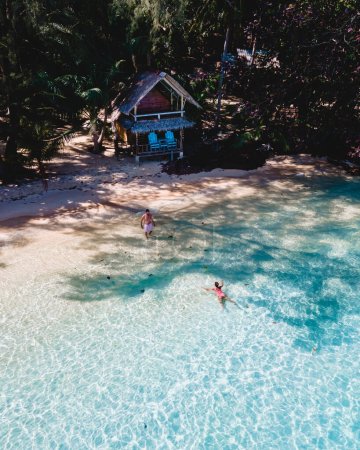 Téléchargez les photos : Koh Wai Island Trat Thaïlande, bungalow en bambou sur la plage. un jeune couple d'hommes et de femmes sur une île tropicale en Thaïlande nageant dans un océan de couleur turque - en image libre de droit
