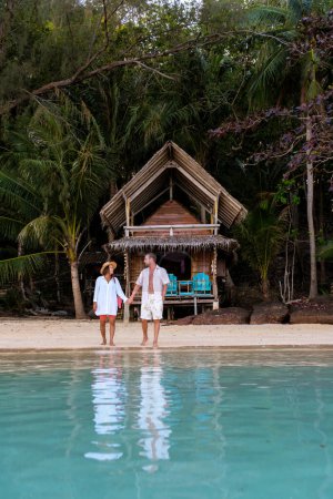 Téléchargez les photos : Un bungalow en bois de cabane de bambou sur la plage avec des palmiers. un jeune couple d'hommes et de femmes sur une île tropicale en Thaïlande en vacances, Koh Wai Island Trat Thaïlande - en image libre de droit
